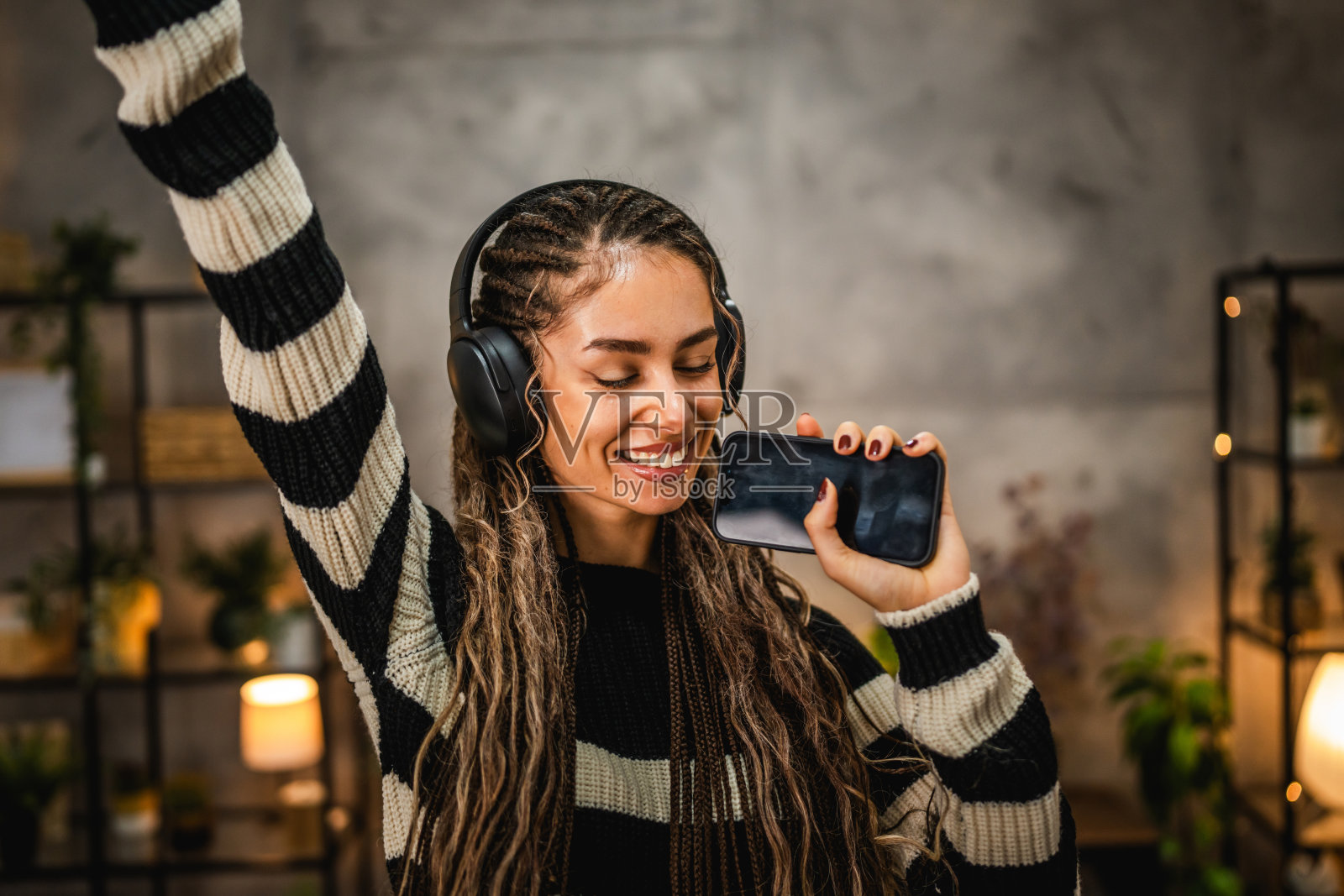 快乐的年轻女性在家中戴着耳机听音乐并唱歌照片摄影图片