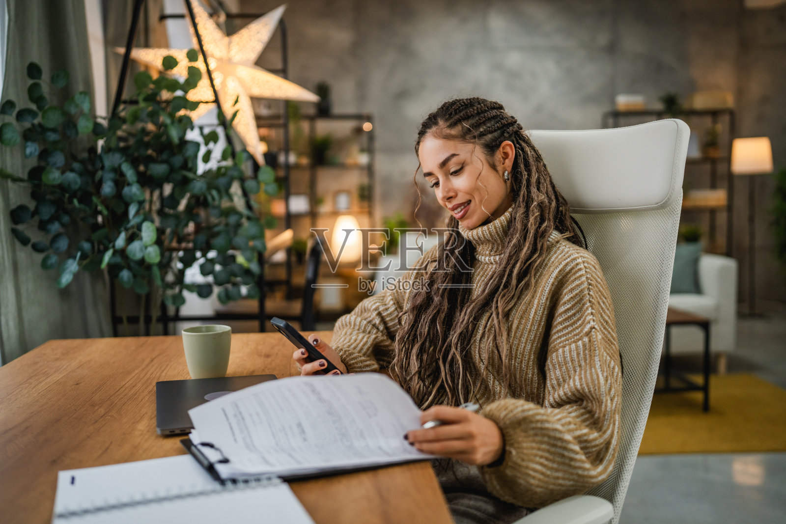 年轻女性在家办公，使用夹板和手机工作照片摄影图片