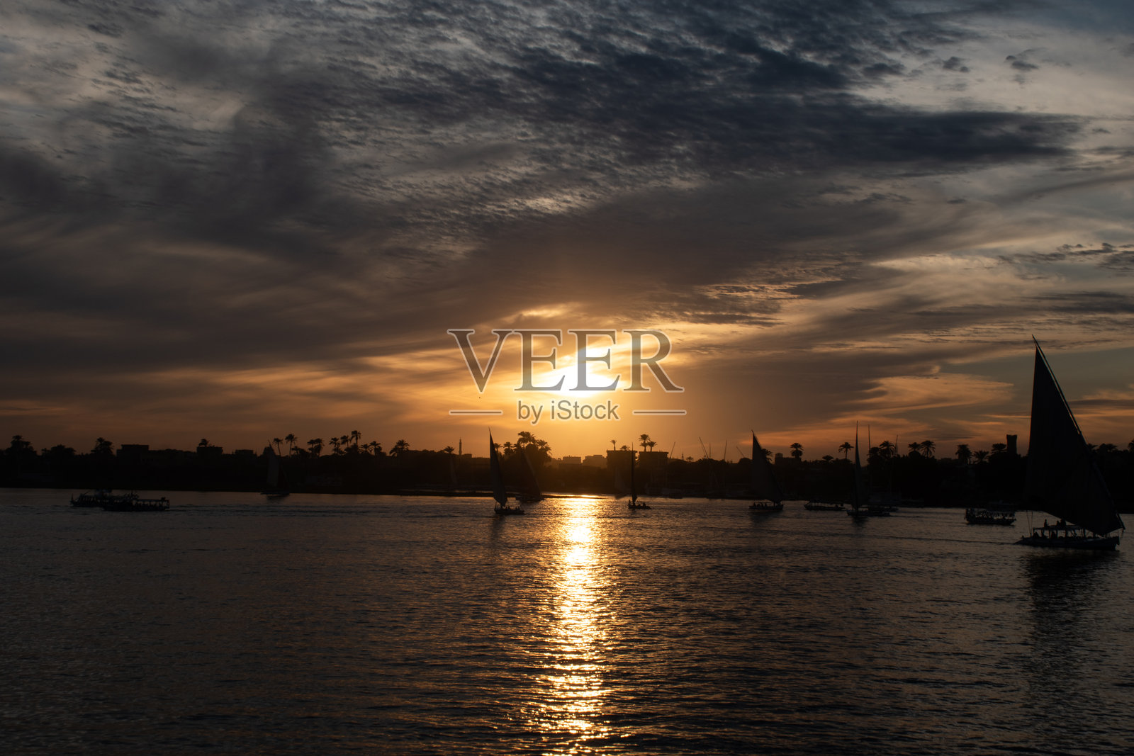 埃及卢克索尼罗河上空的壮丽日落与戏剧性的云彩。照片摄影图片