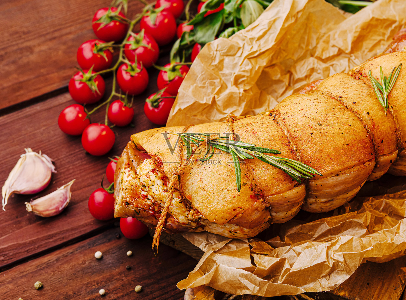 多汁的烤肉裹着香草和香料，搭配新鲜的番茄和大蒜，摆放在木桌上照片摄影图片