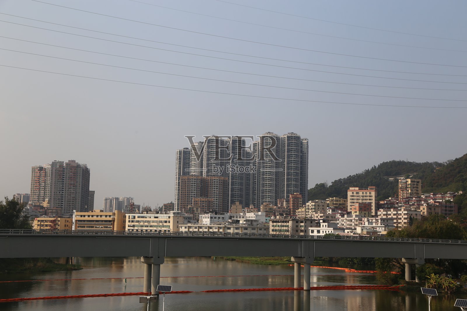 城市天际线的远景，高楼大厦在晴朗的天空和流淌的河流背景下巍然屹立。照片摄影图片