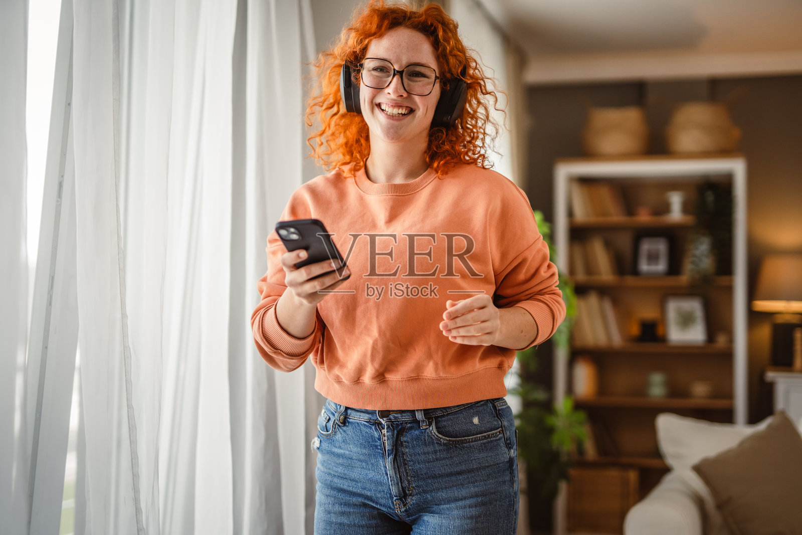 快乐的白人女性戴着耳机跳舞并听音乐照片摄影图片