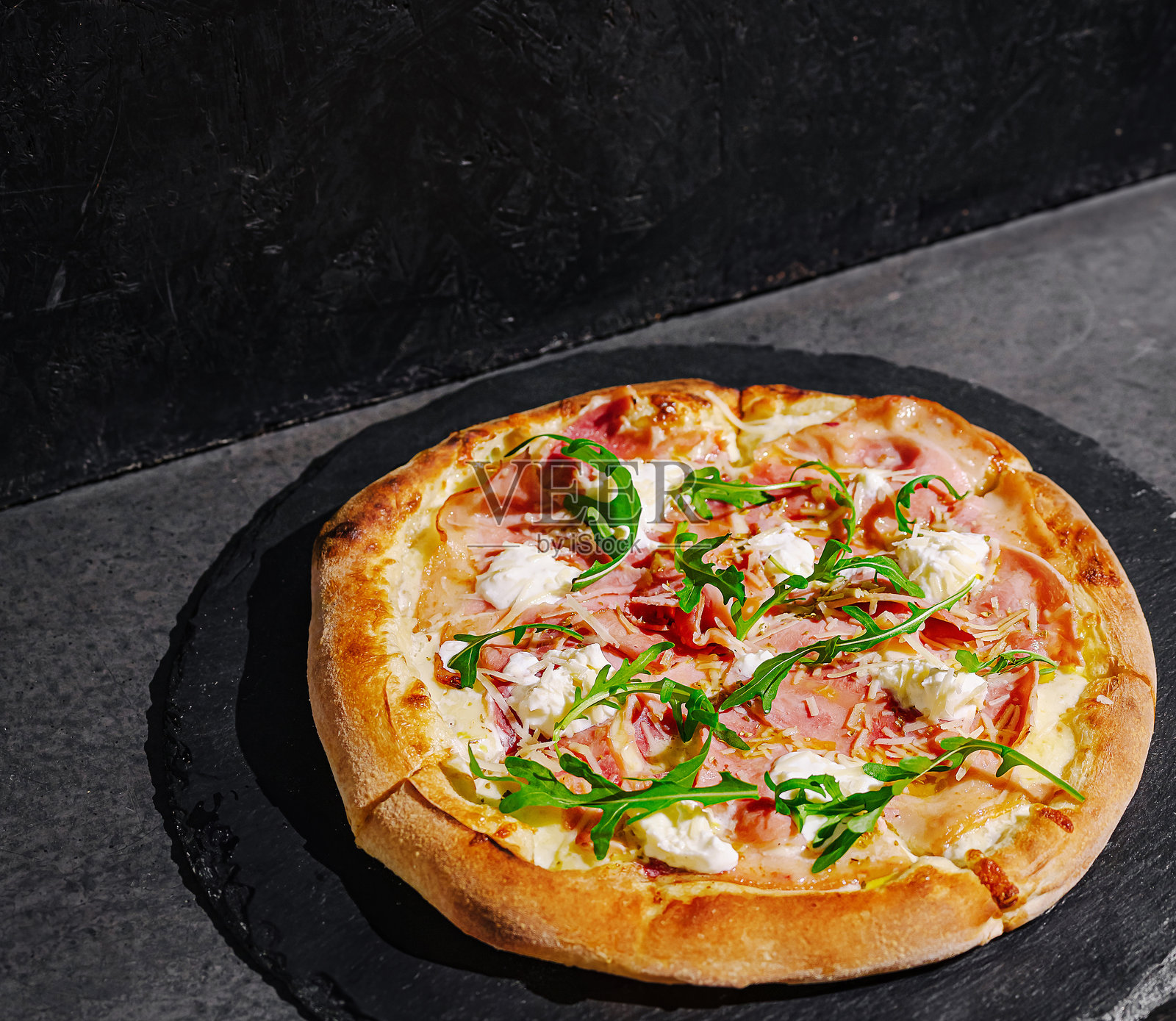 美味的披萨，上面铺满新鲜食材，放在现代厨房环境中的深色石材表面上照片摄影图片