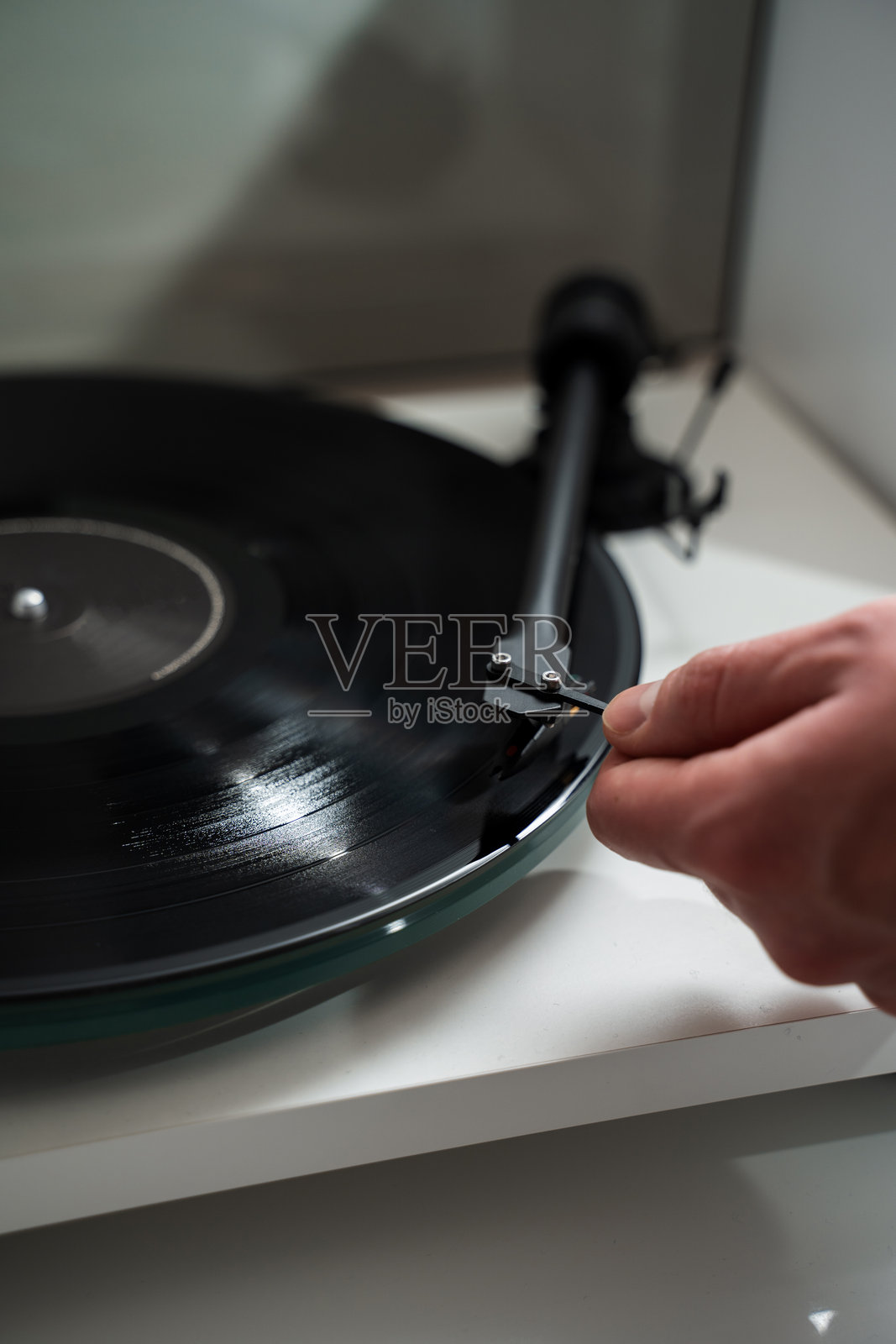 音乐家在黑胶唱机上调整音臂。音乐爱好者在播放复古音乐之前，手持音臂。照片摄影图片