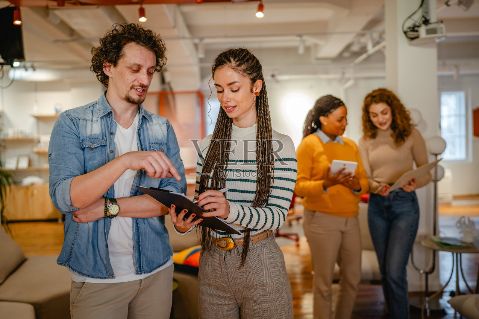 两位同事在办公室一起查看剪贴板上的信息照片摄影图片