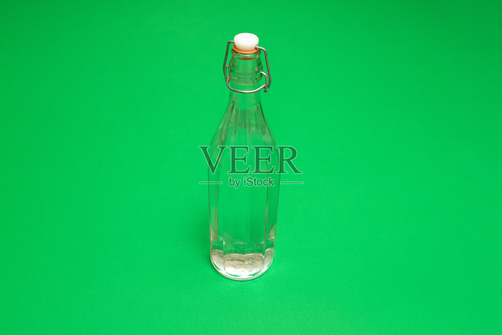 绿色背景上装满清澈液体的玻璃翻盖瓶照片摄影图片