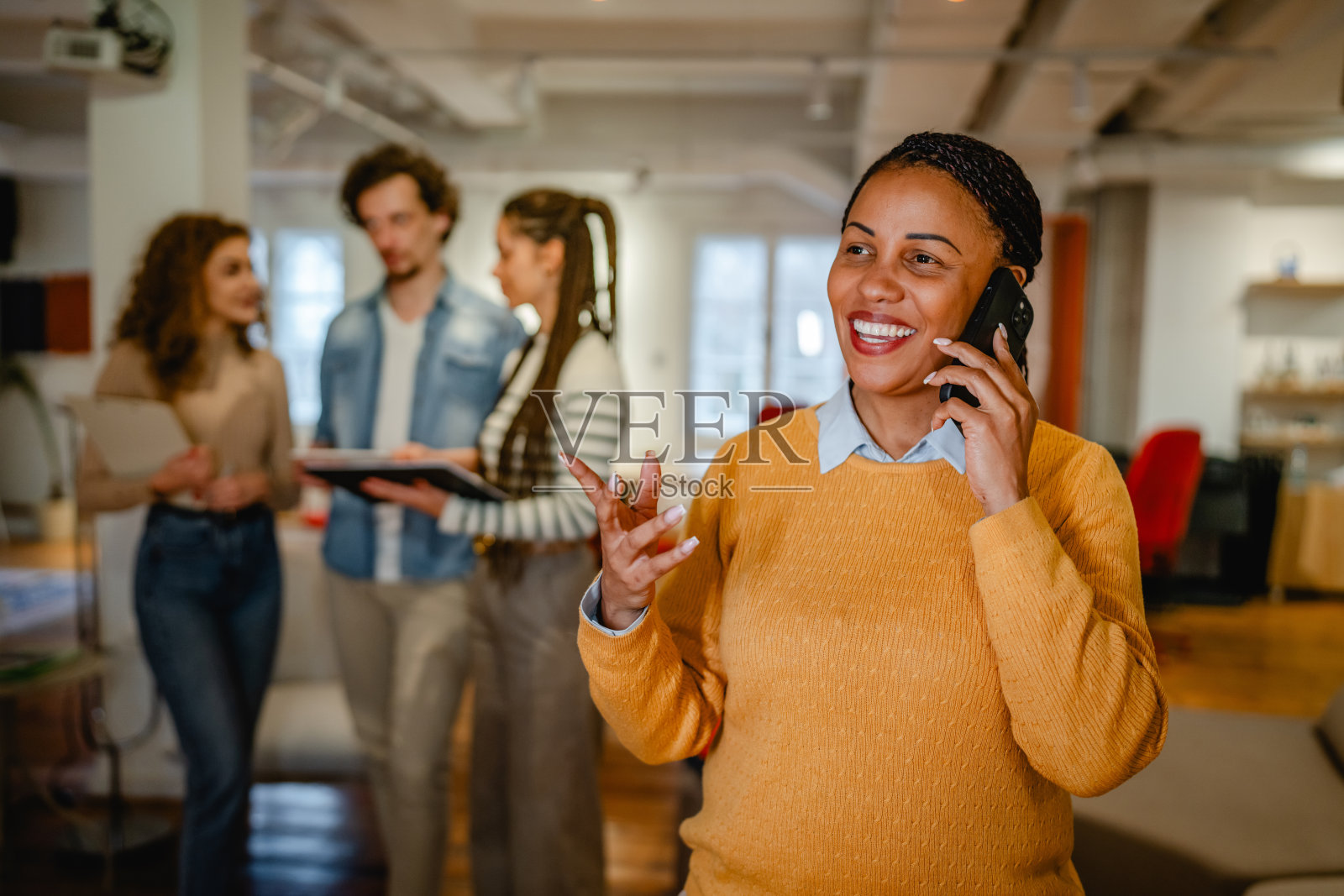 非裔美国女性商务人士在办公室里用手机通话照片摄影图片