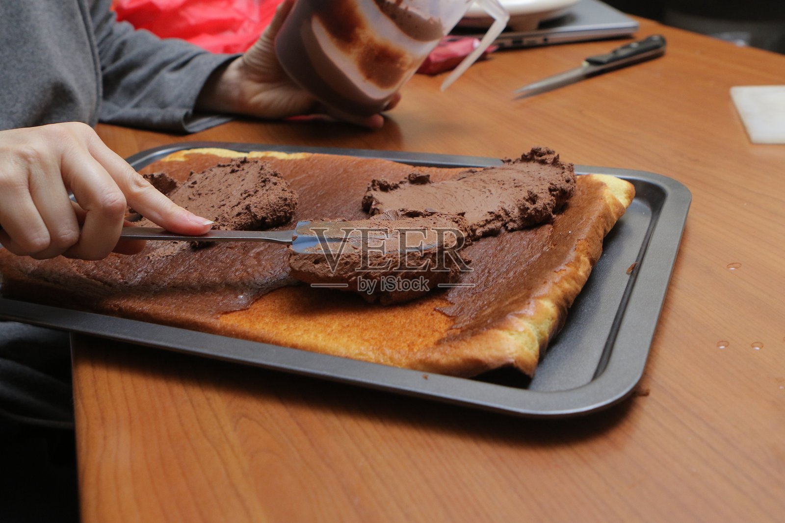 糕点师在瑞士卷饼上涂抹巧克力奶油照片摄影图片