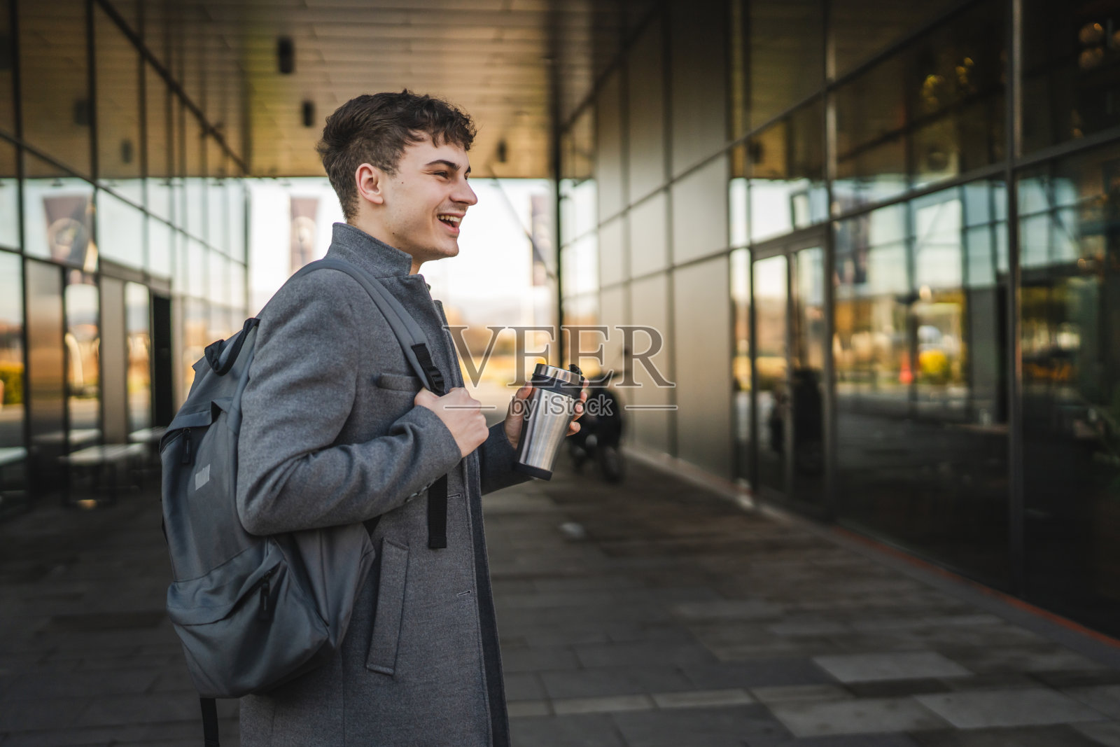 男子在现代建筑间休息时喝咖啡照片摄影图片