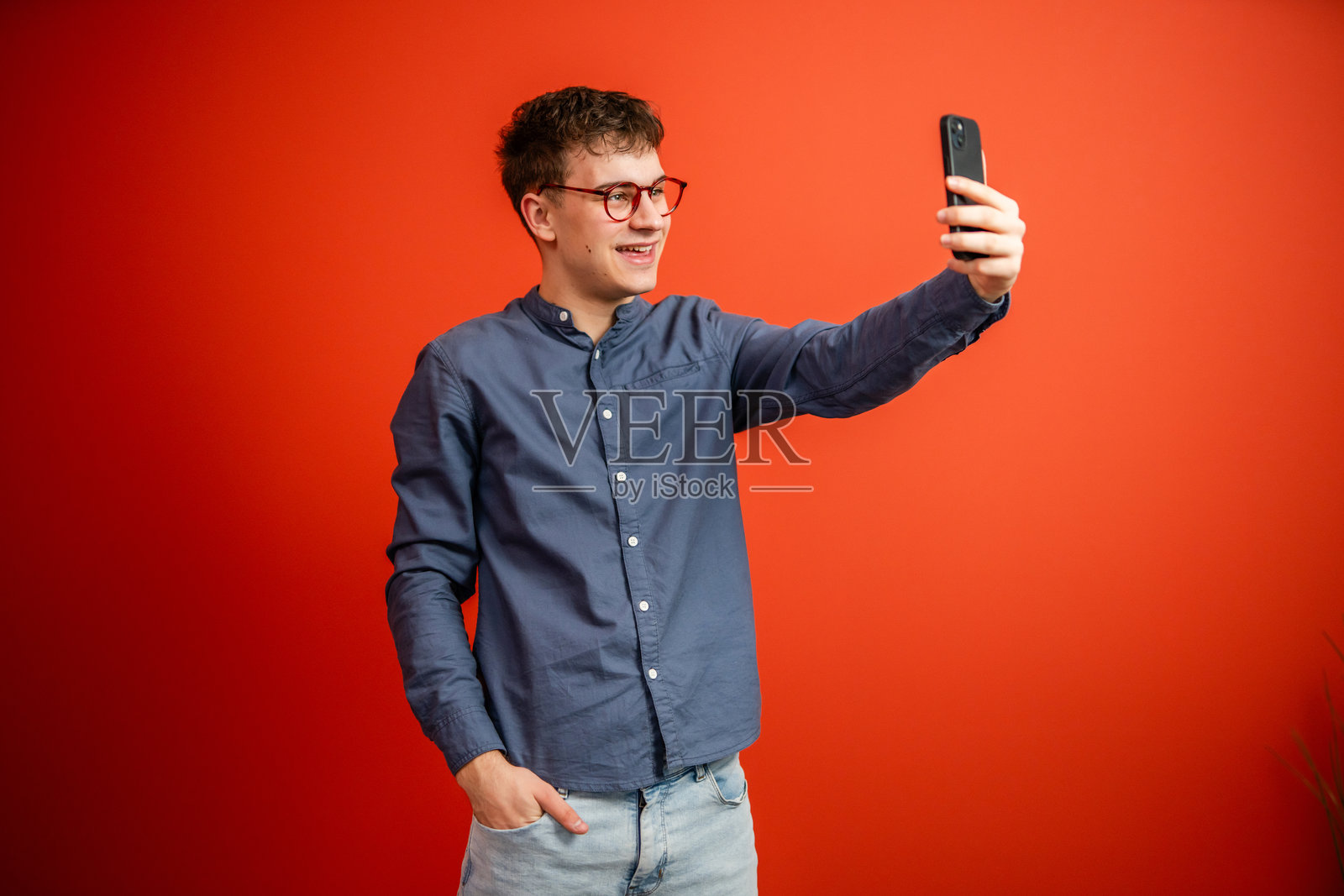年轻男子在红色背景下拍摄自拍照照片摄影图片