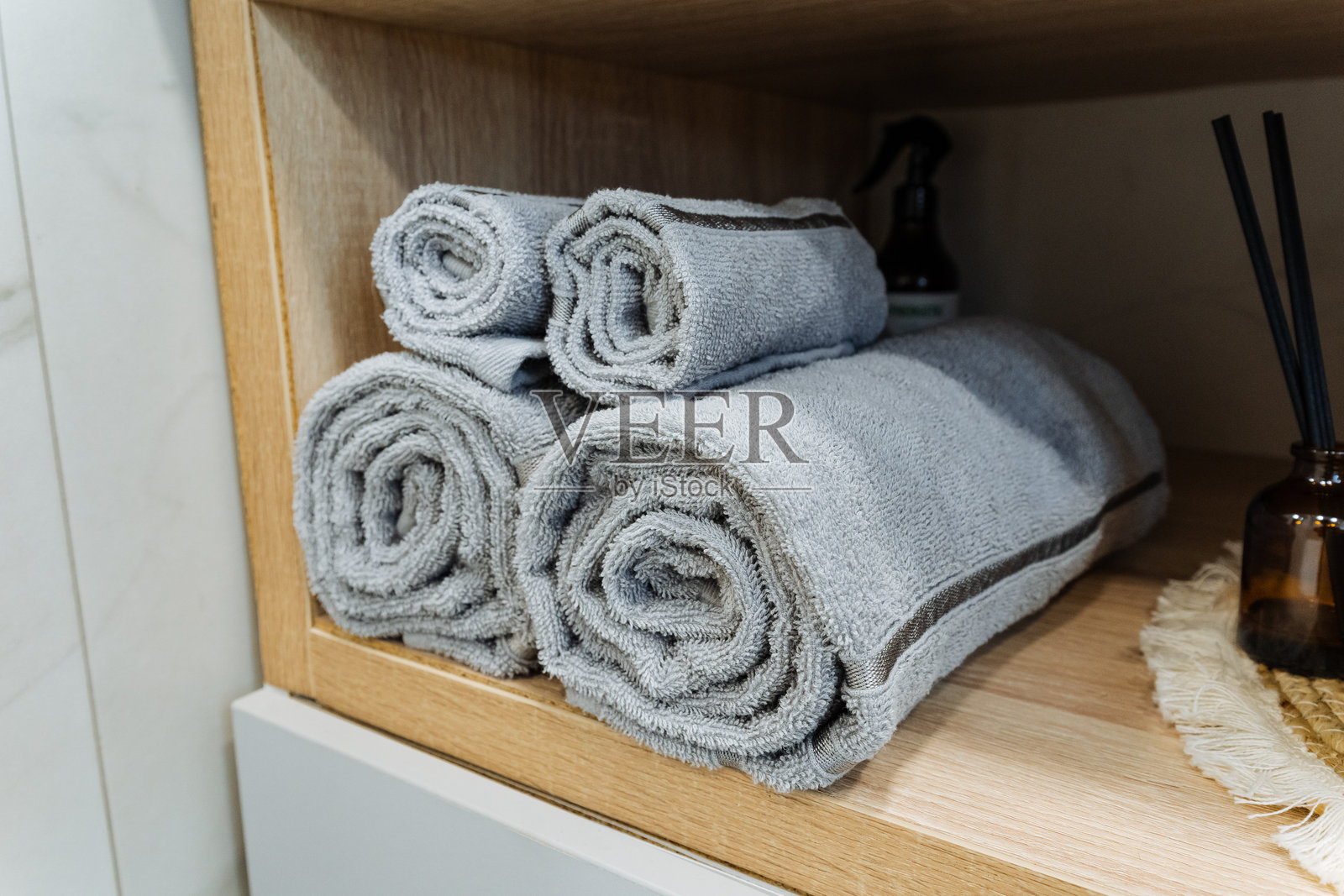 一大堆柔软的毛巾整齐地叠放在坚固的架子上，随时可以在浴室使用或作为厨房的时尚装饰，提升空间的美感。照片摄影图片