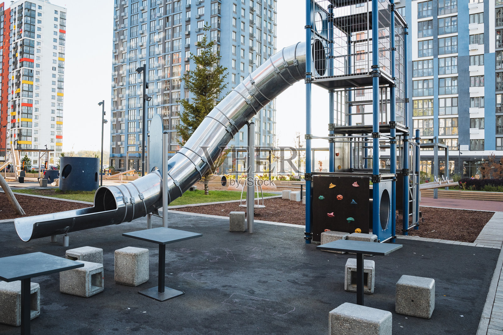 一个令人愉快的游乐场，设有各种舒适的桌椅，以及一个供孩子们安全玩耍的刺激滑梯。照片摄影图片