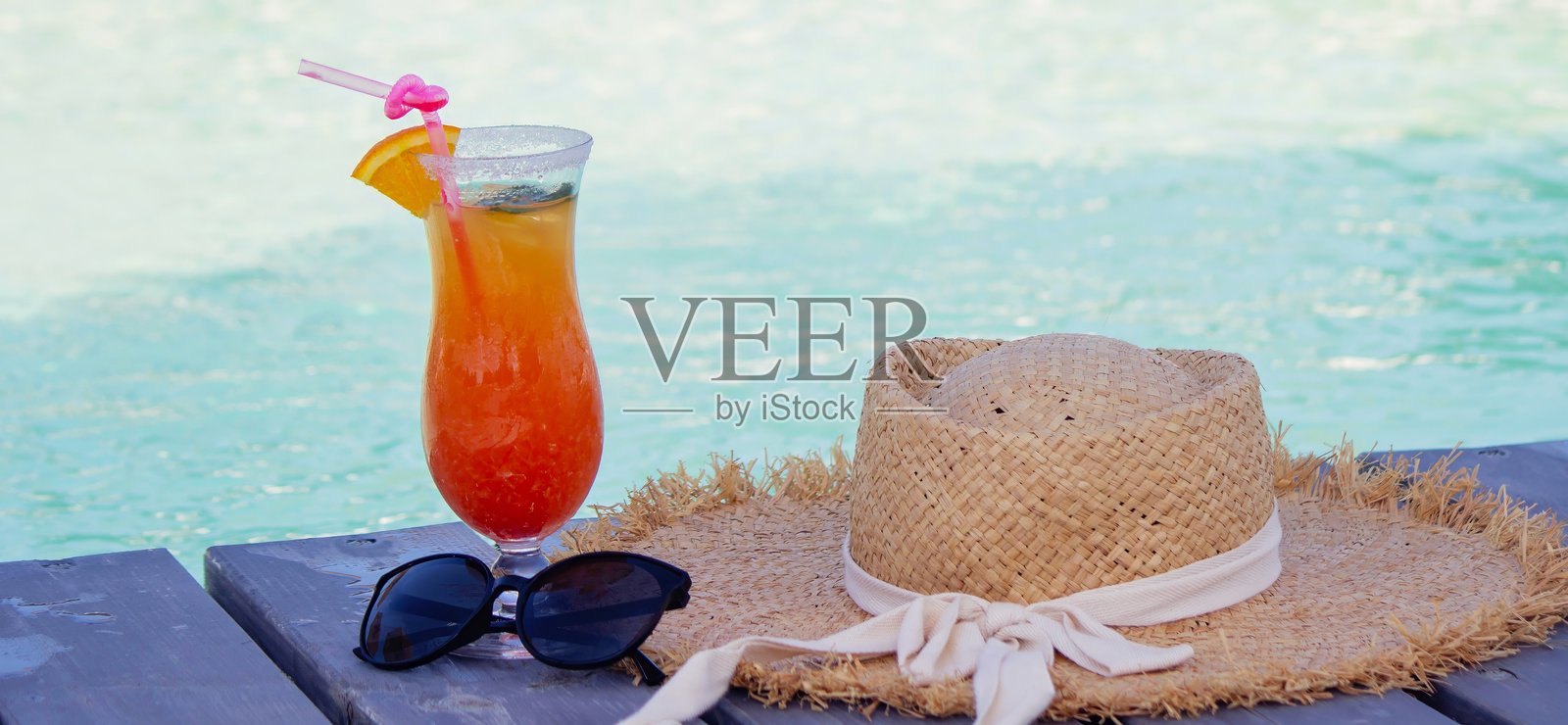 泳池边的一杯美味鸡尾酒、帽子和太阳镜照片摄影图片