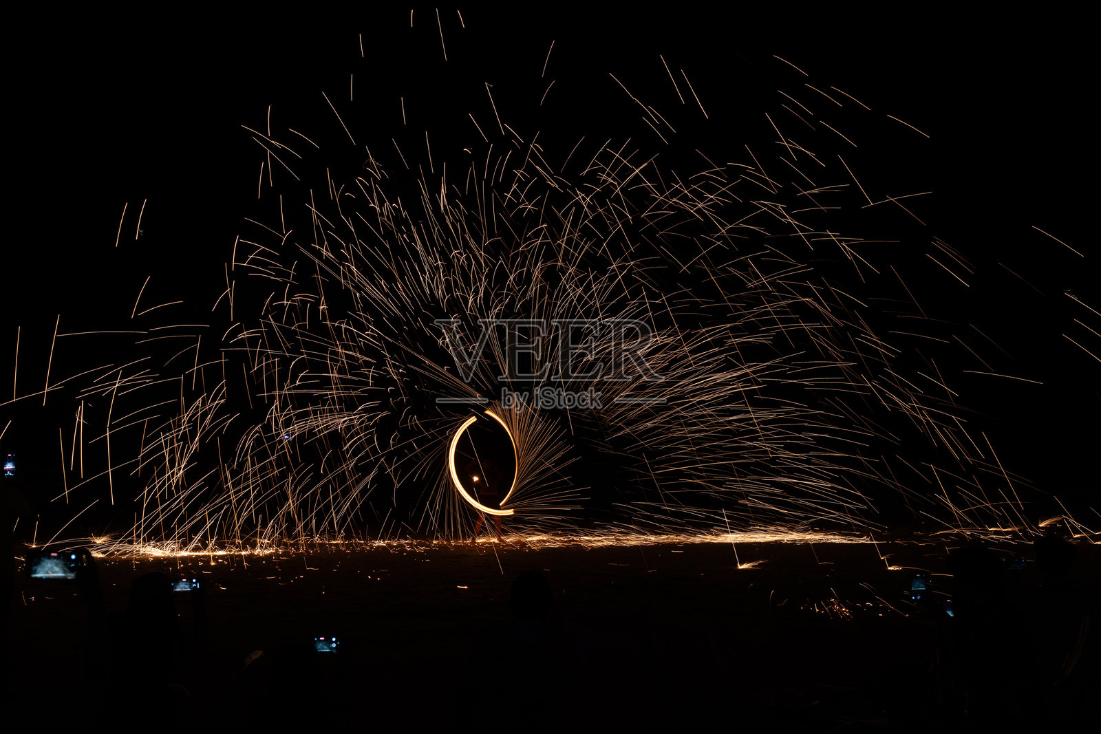 夜间地面上的秋千火舞表演，长时间曝光照片摄影图片