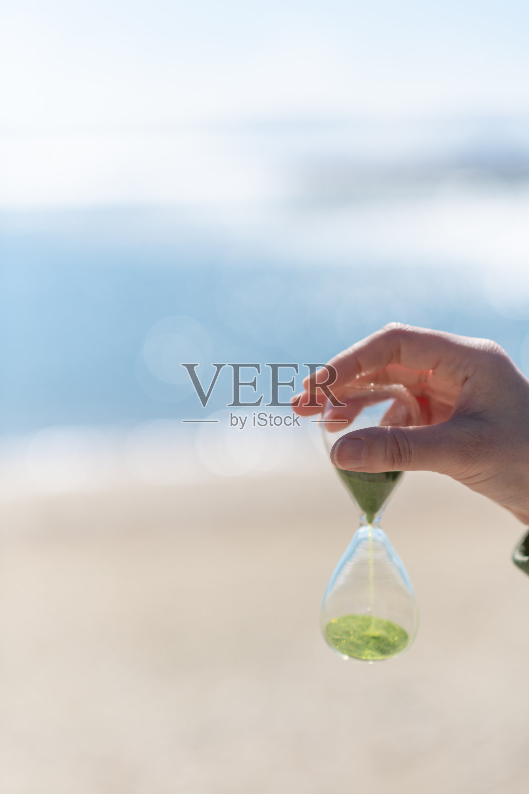 在海滩上拿着沙漏的人照片摄影图片