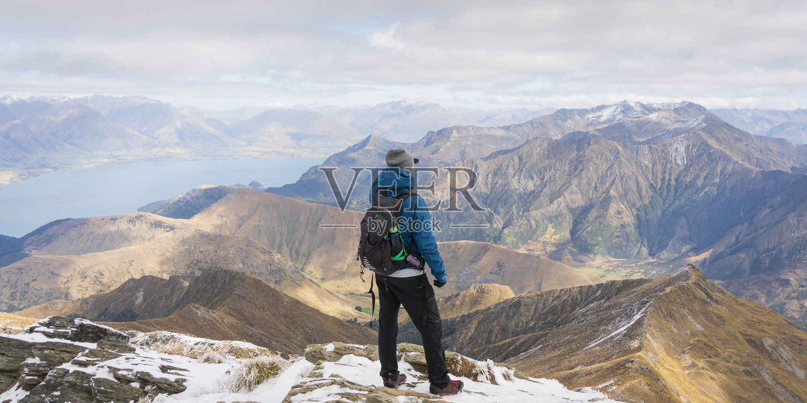 男性登山者站在山顶，欣赏美丽的阿尔卑斯湖泊风景照片摄影图片