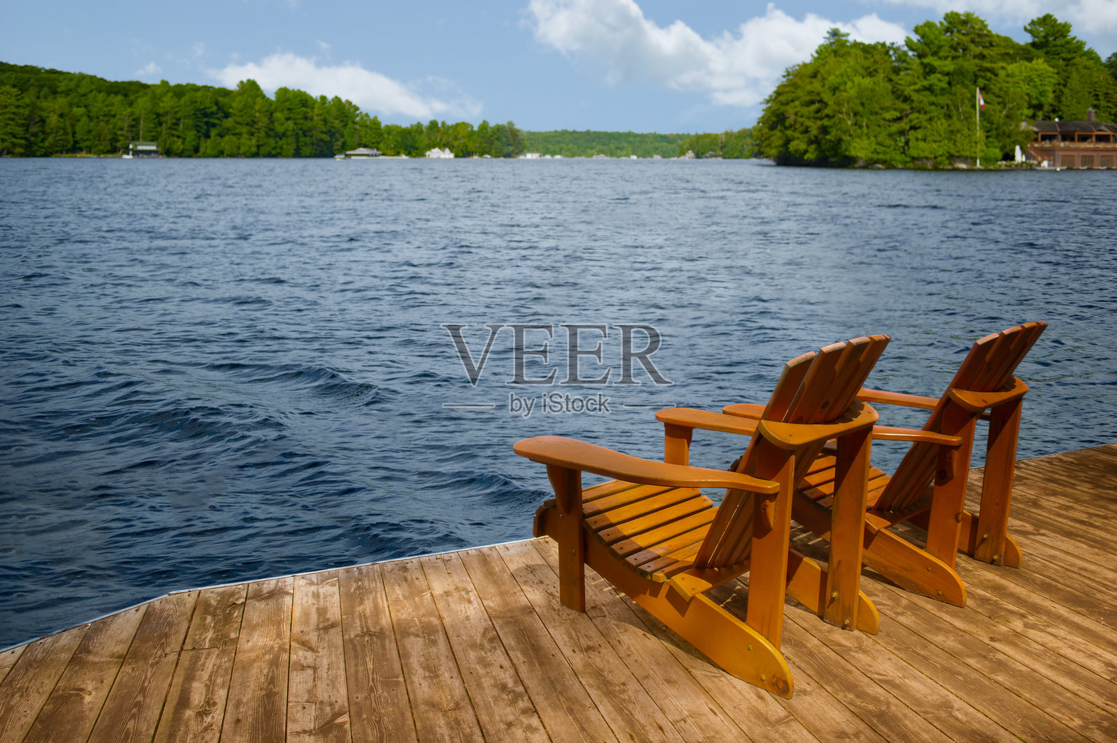 码头上的阿迪朗达克椅，湖面微波荡漾，远处是小屋。照片摄影图片