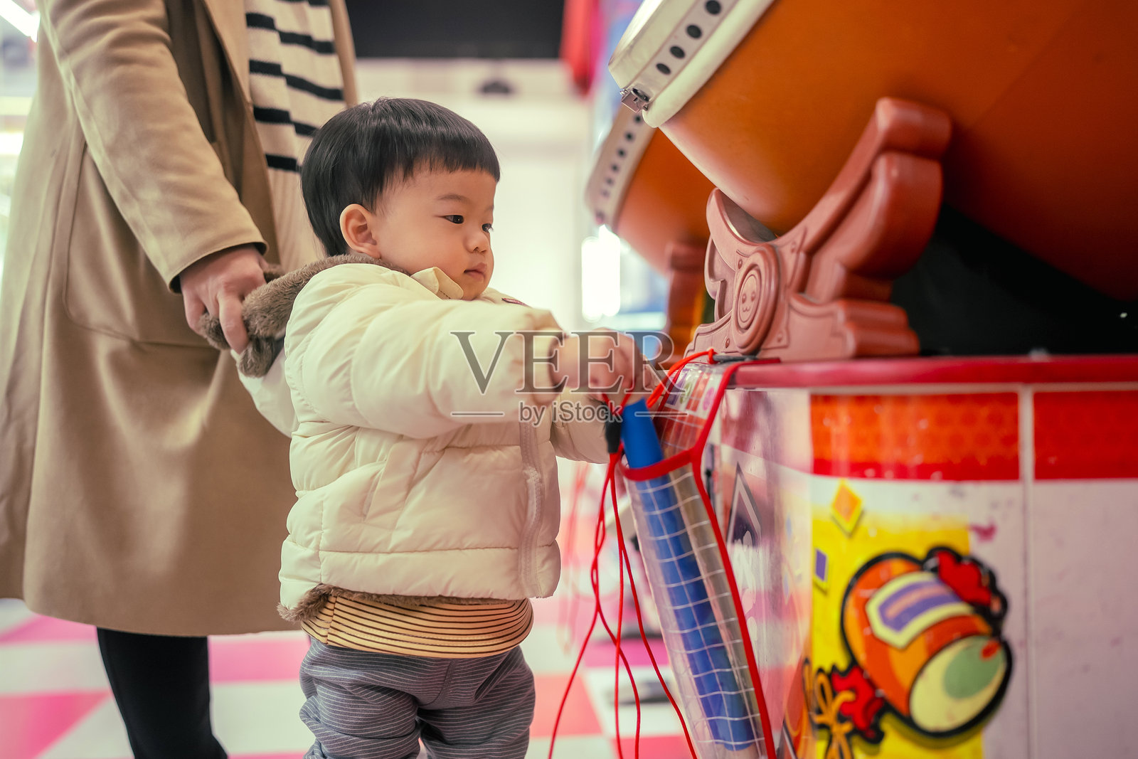旅行概念：亚洲家庭，妈妈和儿子，积极情绪，亚洲母亲和幼儿穿着休闲服装，在游戏中心的游戏机旁奔跑玩耍，满脸笑容，快乐大笑。照片摄影图片