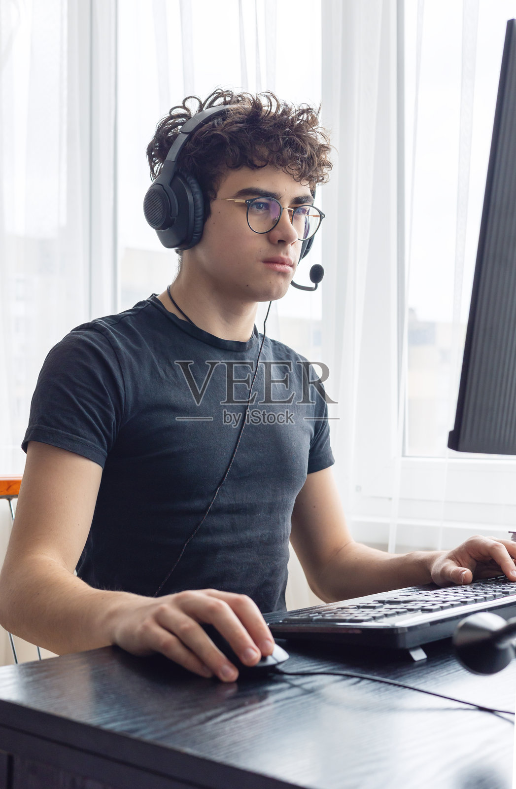 青少年电子竞技选手专注于游戏。青少年利用科技进行学习和游戏。青少年玩家在电脑上游戏。在家在线学习。在家用电脑学习数学。留白空间。照片摄影图片