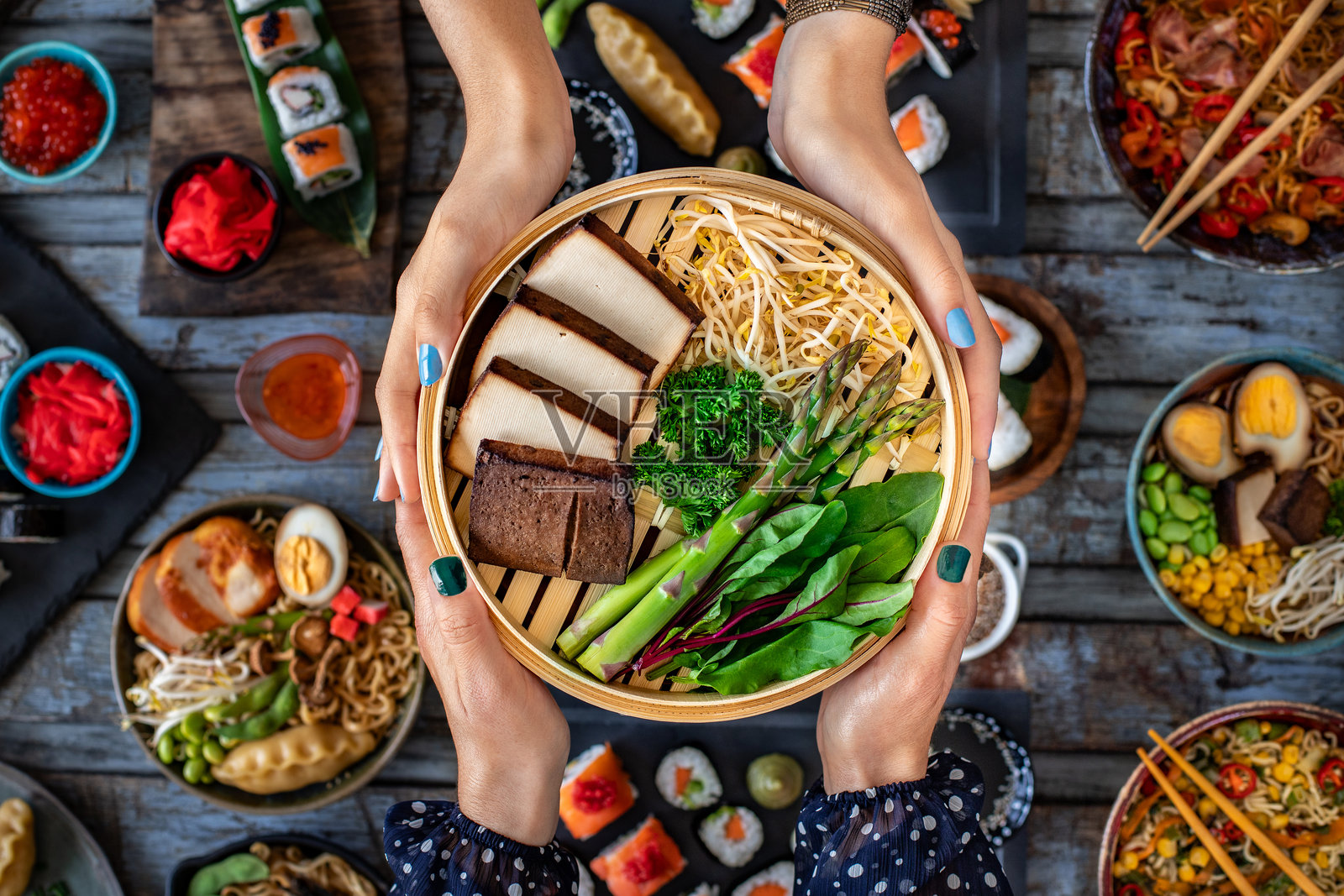 两位女性的手握着一碗熏豆腐。照片摄影图片