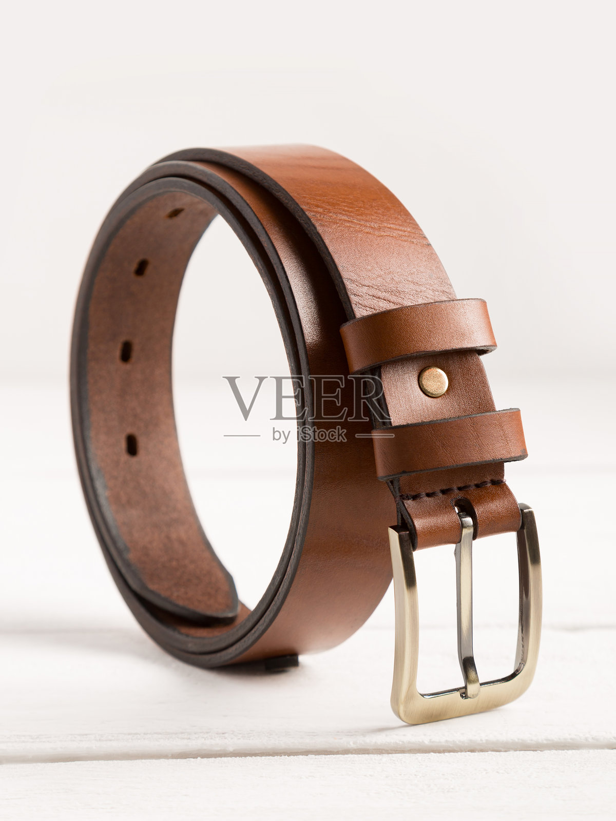 棕色皮带放在白色木质背景上。照片摄影图片