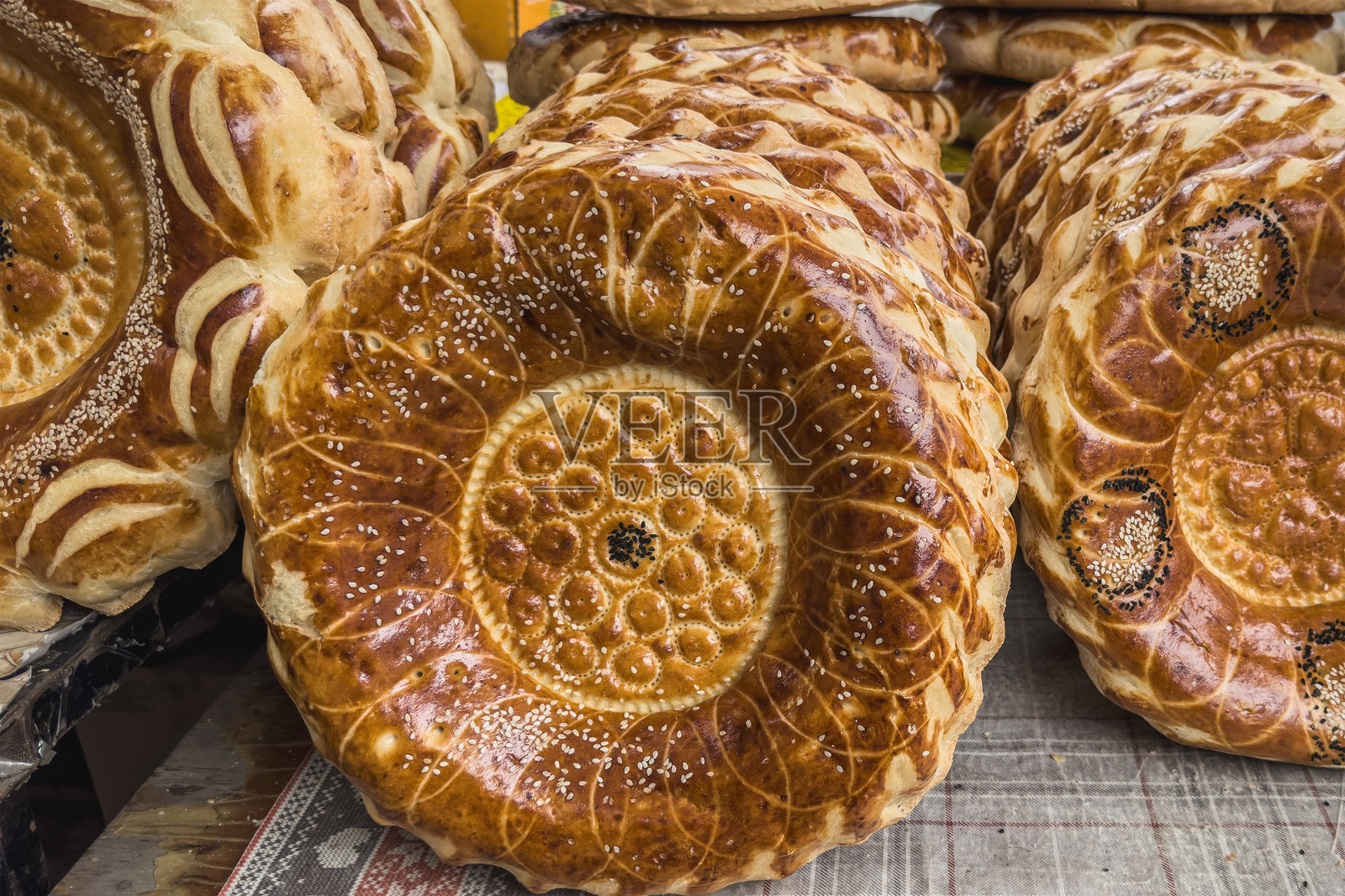 比什凯克市场摊位上的传统中亚扁面包。日常吉尔吉斯食品。新鲜的扁面包上有复杂的图案。照片摄影图片