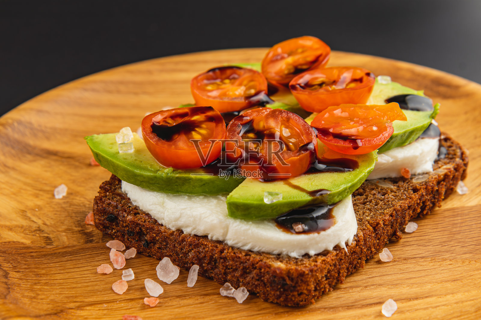 美味的开放式三明治，上面放有新鲜的配料，摆放在木盘上照片摄影图片