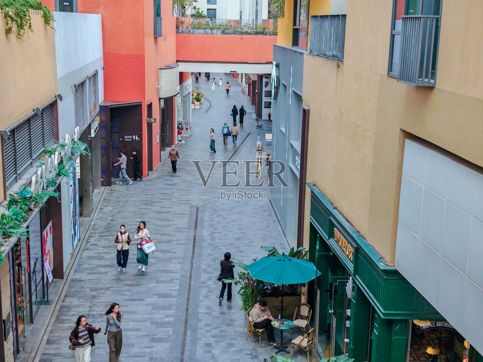 行人漫步在中国深圳上坡的一个充满活力的购物中心的户外步道上。阳光明媚的日子里，五彩斑斓的建筑沿街而立。照片摄影图片