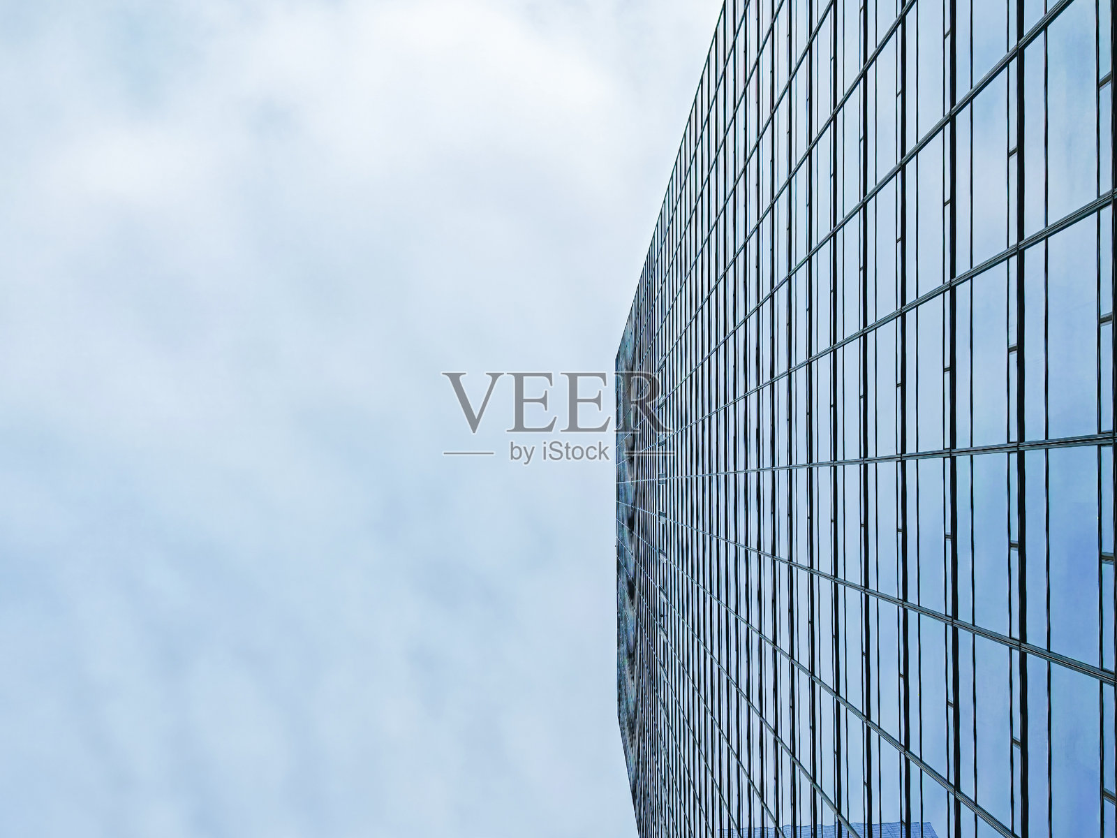 中国深圳上坡的现代建筑。一座购物中心的玻璃外立面映照着天空中的云朵。照片摄影图片