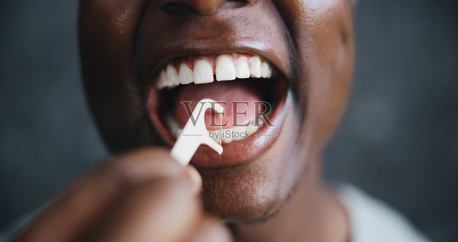 黑人男性使用牙线和清洁牙齿以保持口腔卫生、牙齿护理或牙龈健康。自我护理、早晨例行活动和预防蛀牙，背景为黑色的特写镜头。照片摄影图片