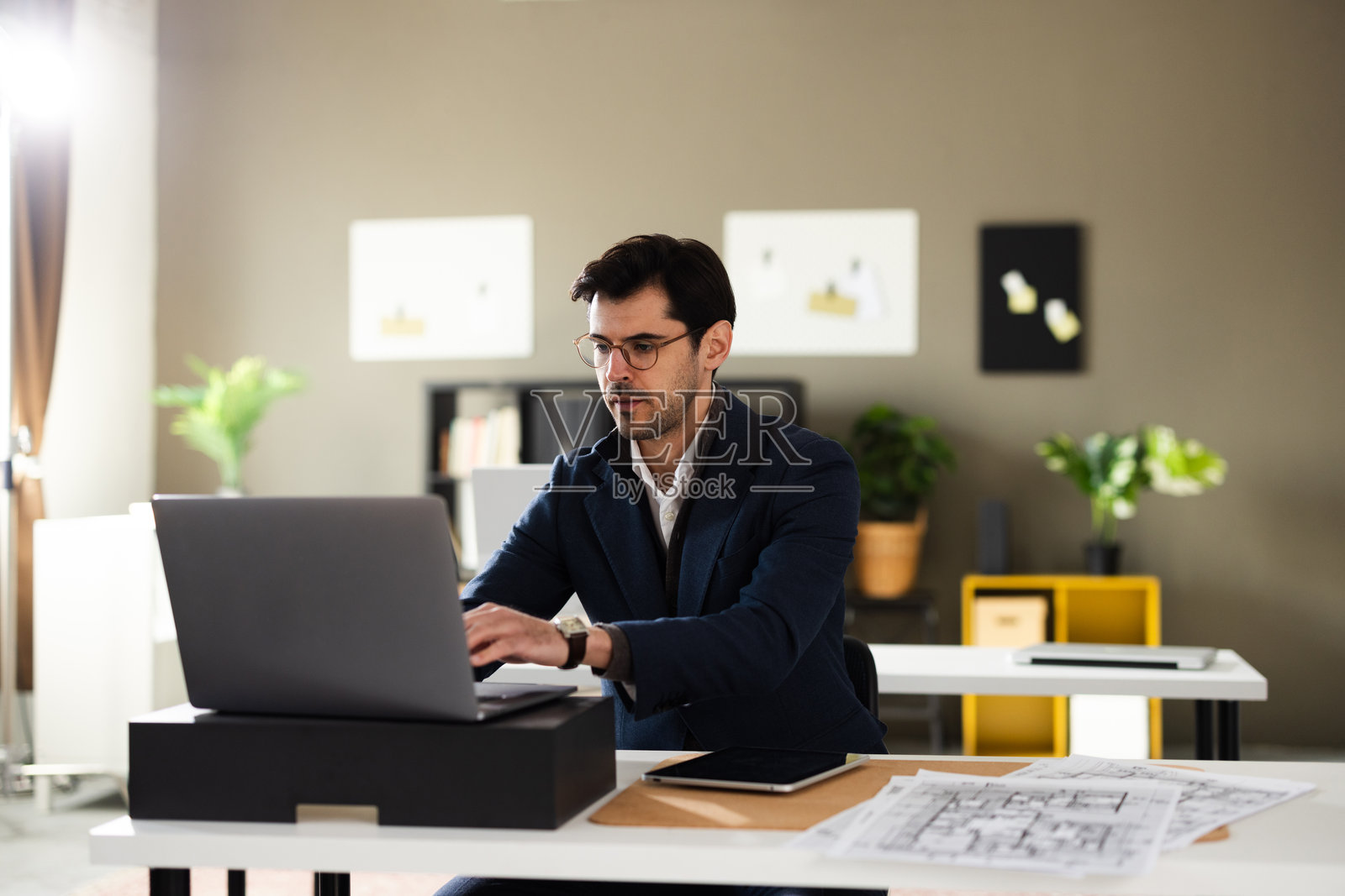 一位建筑师正在桌子上绘制建筑项目的蓝图照片摄影图片