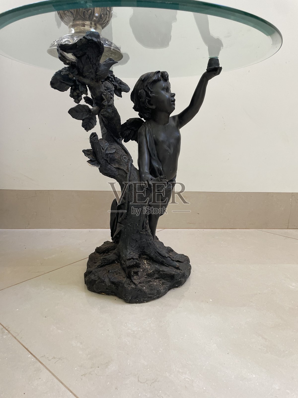 古代雕塑托着一张玻璃桌子照片摄影图片