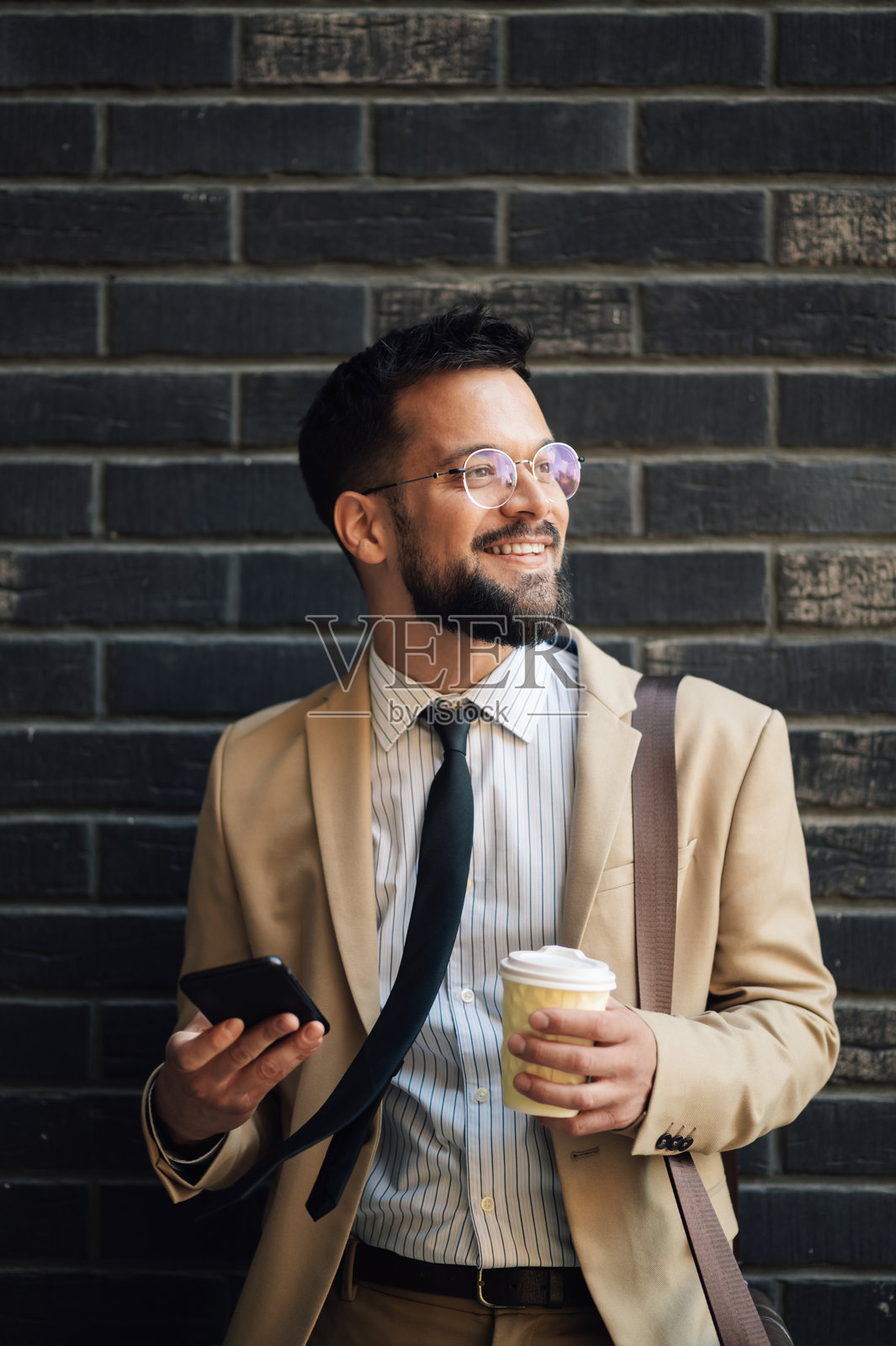 微笑的商人手持咖啡并使用智能手机照片摄影图片