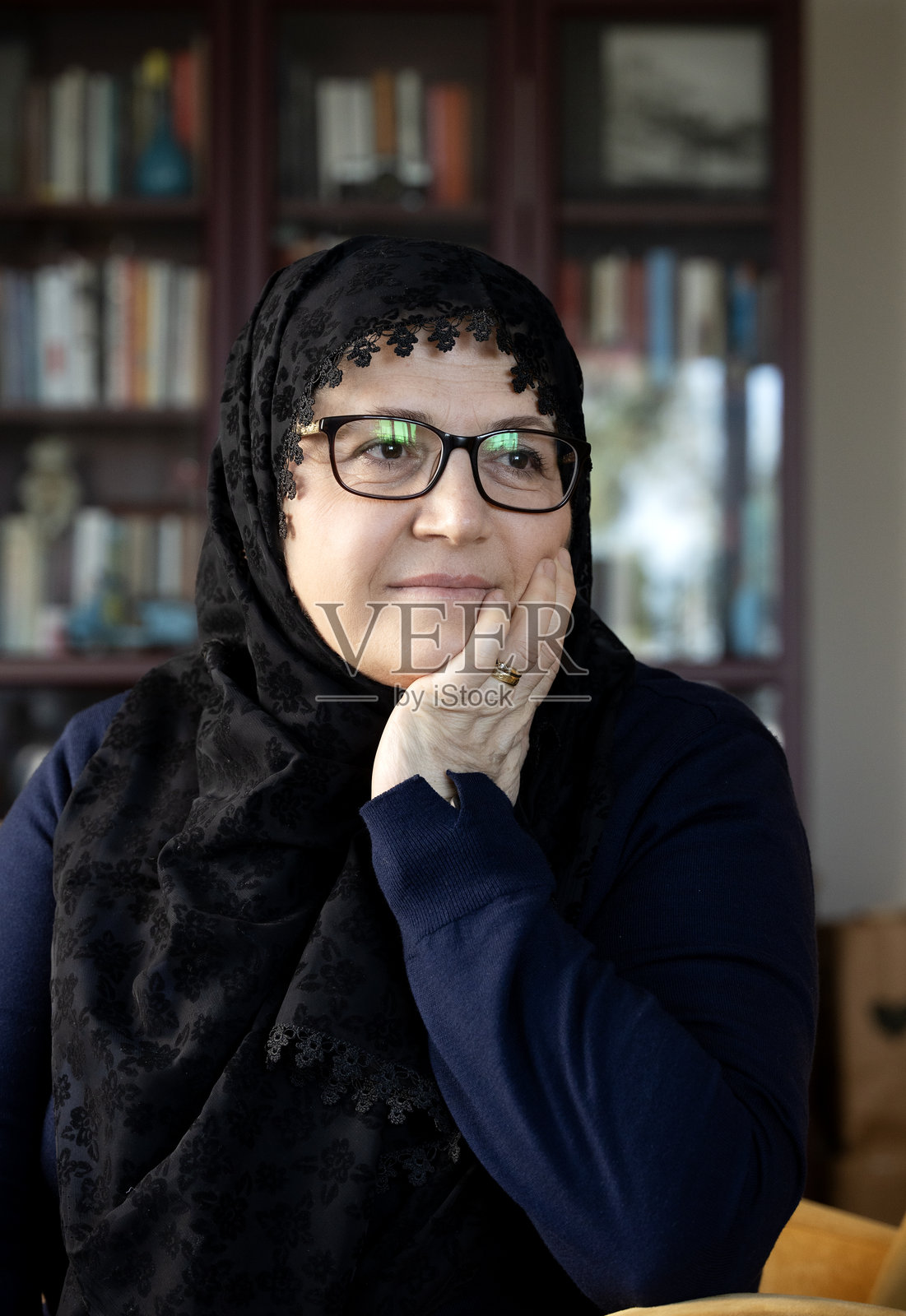 中年穆斯林女性戴着头巾坐在家中照片摄影图片