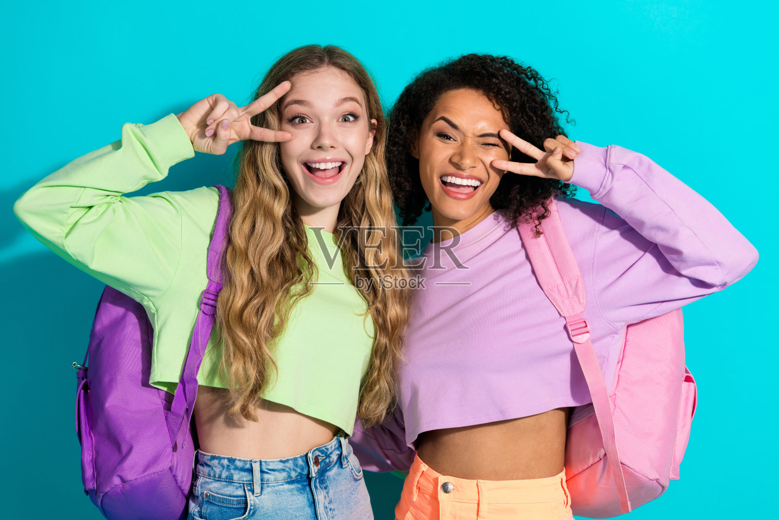 快乐的女性朋友们穿着色彩鲜艳的休闲服装，在生动的青绿色背景前摆姿势照片摄影图片