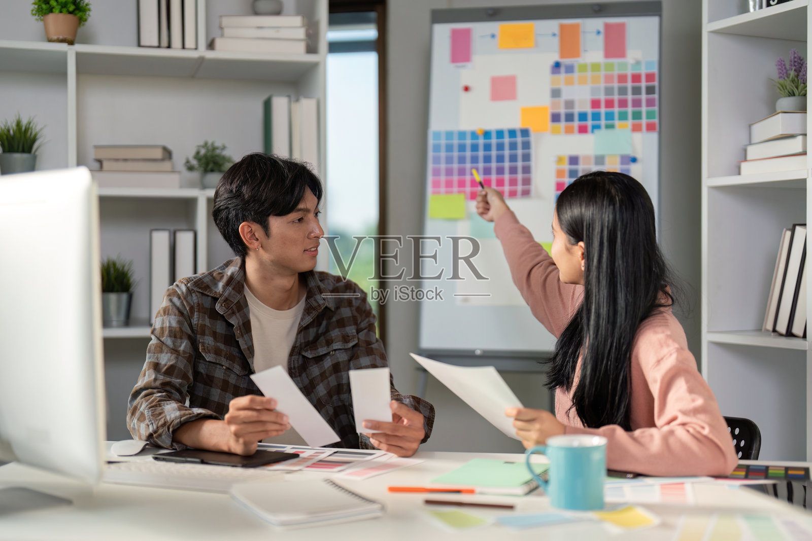 多元化的平面设计团队在充满活力的工作空间中讨论颜色选择和项目概念。照片摄影图片