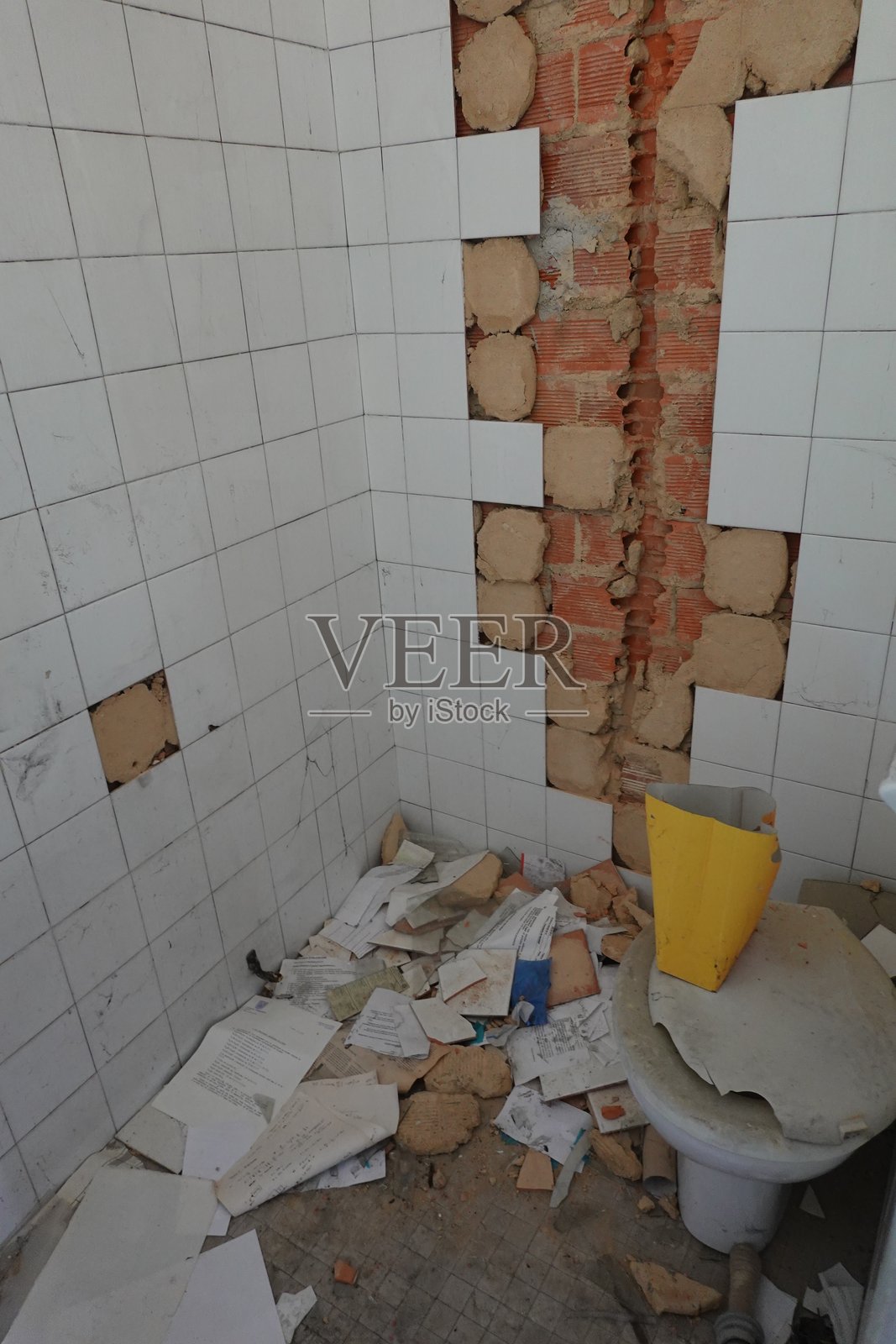 废弃的卫生间，破碎的瓷砖和散落的纸张照片摄影图片