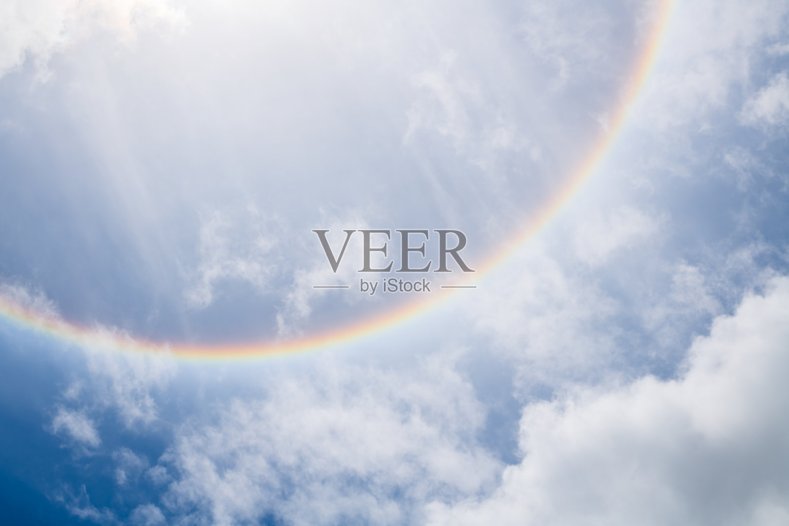 阳光周围的彩虹色彩在云层和天空中。奇妙美丽的日晕现象。自然背景。照片摄影图片