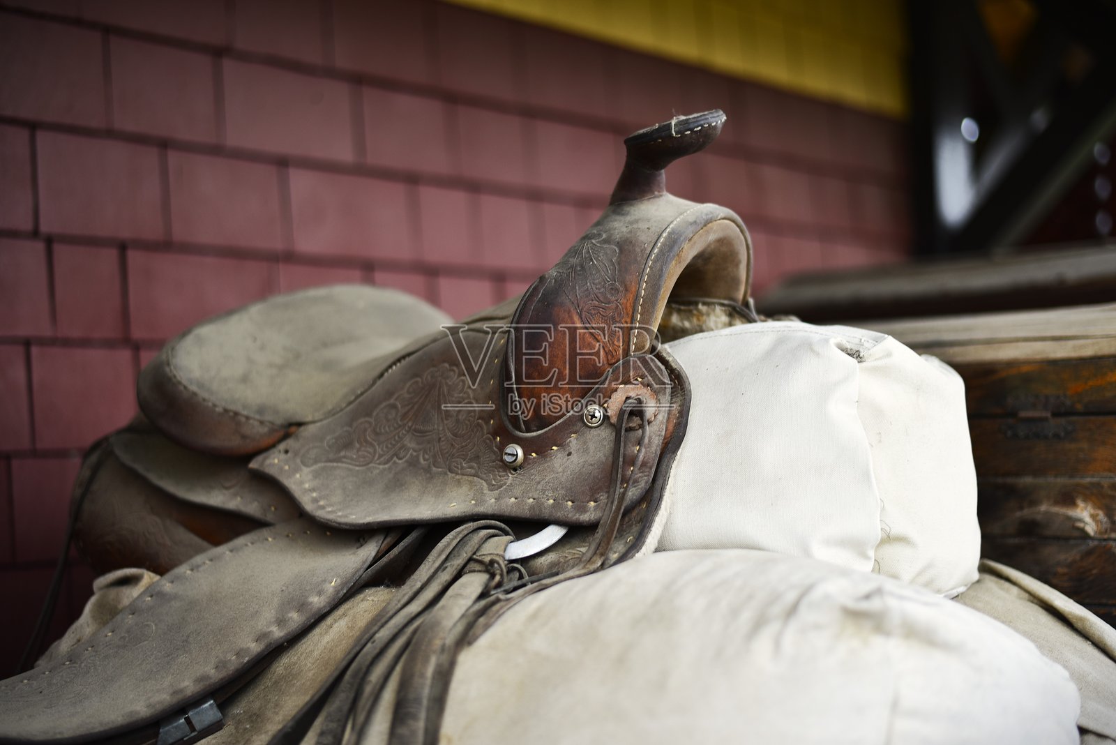 一把古老的鞍子，磨损且风化，皮革褪色并开裂。照片摄影图片