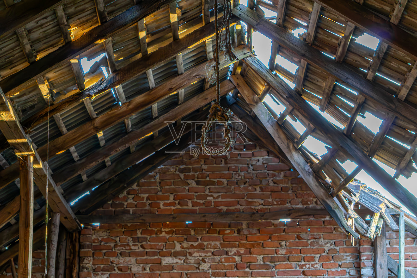 老旧破败的砖砌谷仓内部视图，木质屋顶。谷仓内破损的木质屋顶，屋顶上的洞。照片摄影图片