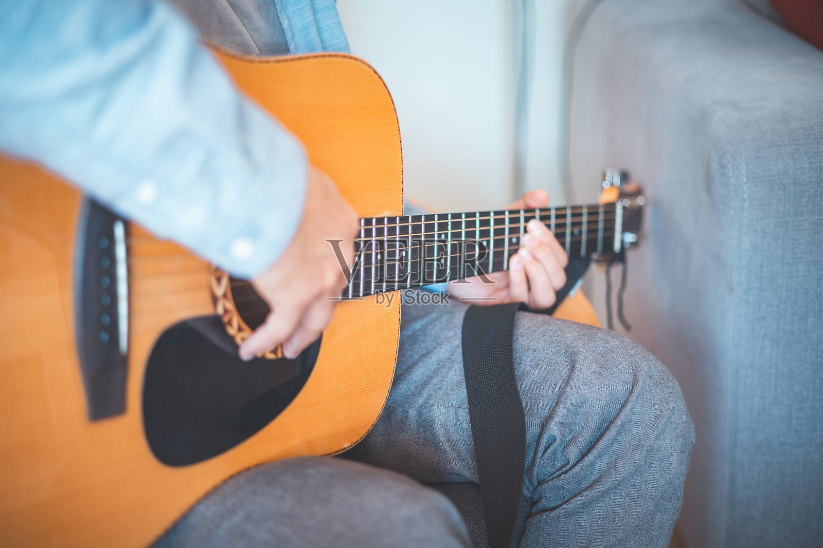 特写镜头下，音乐家在温馨的家中弹奏着原声吉他，沉浸在音乐中。他的休闲风格、温暖的灯光和轻松的氛围营造出一个宁静、艺术和鼓舞人心的时刻。照片摄影图片