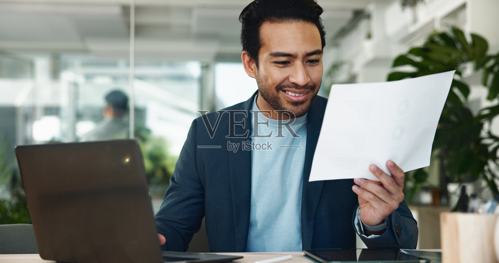 办公室里微笑的男人与商业文件、笔记本电脑，进行财务报表、公司账户和审查。专业的会计师或对预算报告感到满意，进行风险管理或数据分析。照片摄影图片