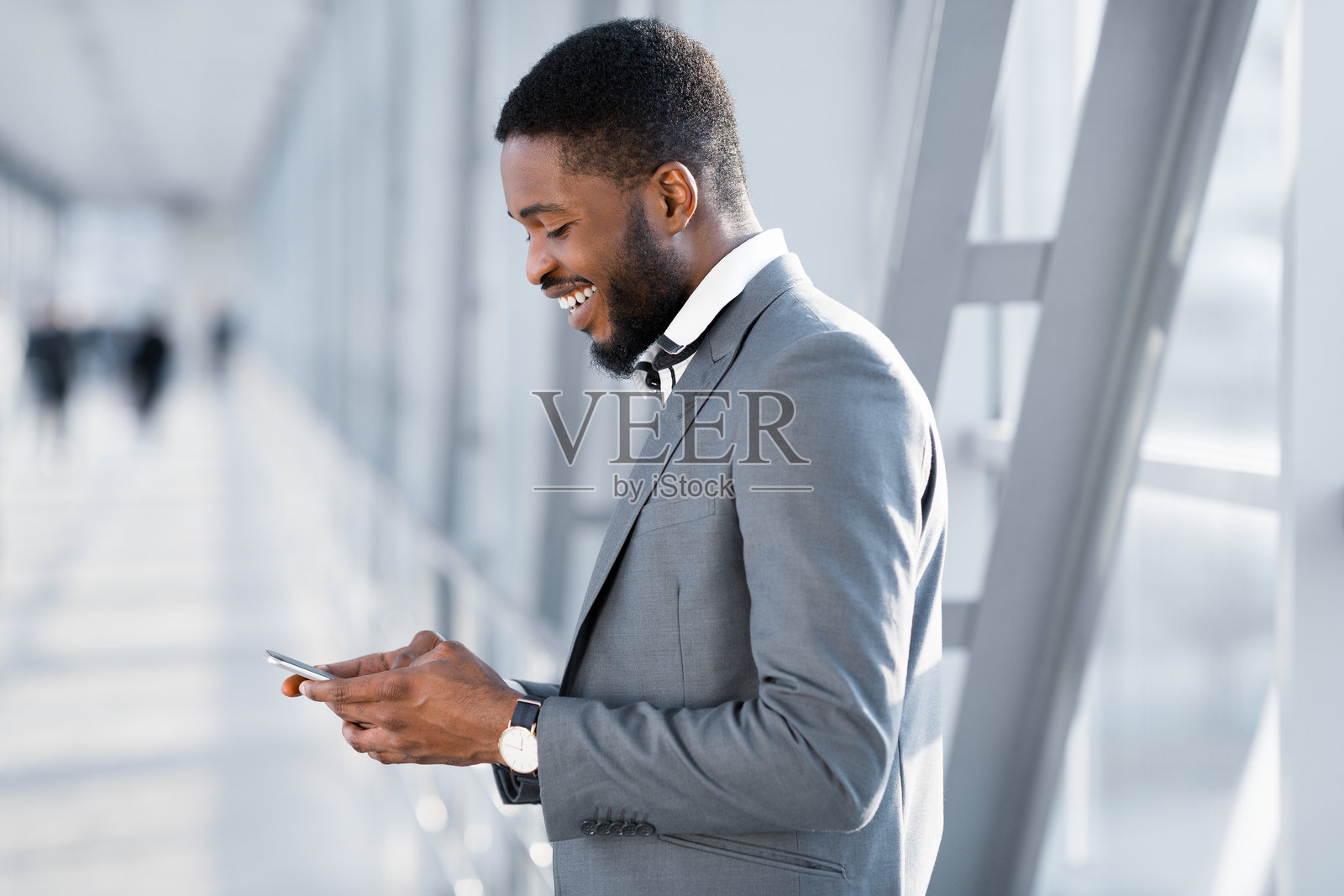 始终保持联系。商人正在手机上发短信，等待航班。照片摄影图片