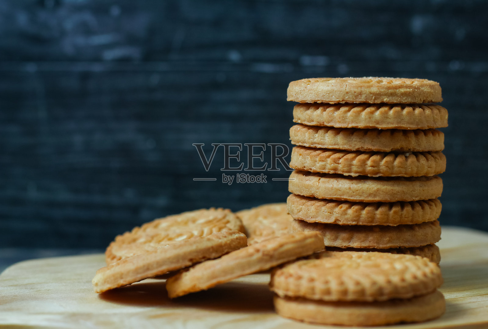 一堆美味的杏仁饼干放在木板上，背景为深色。照片摄影图片