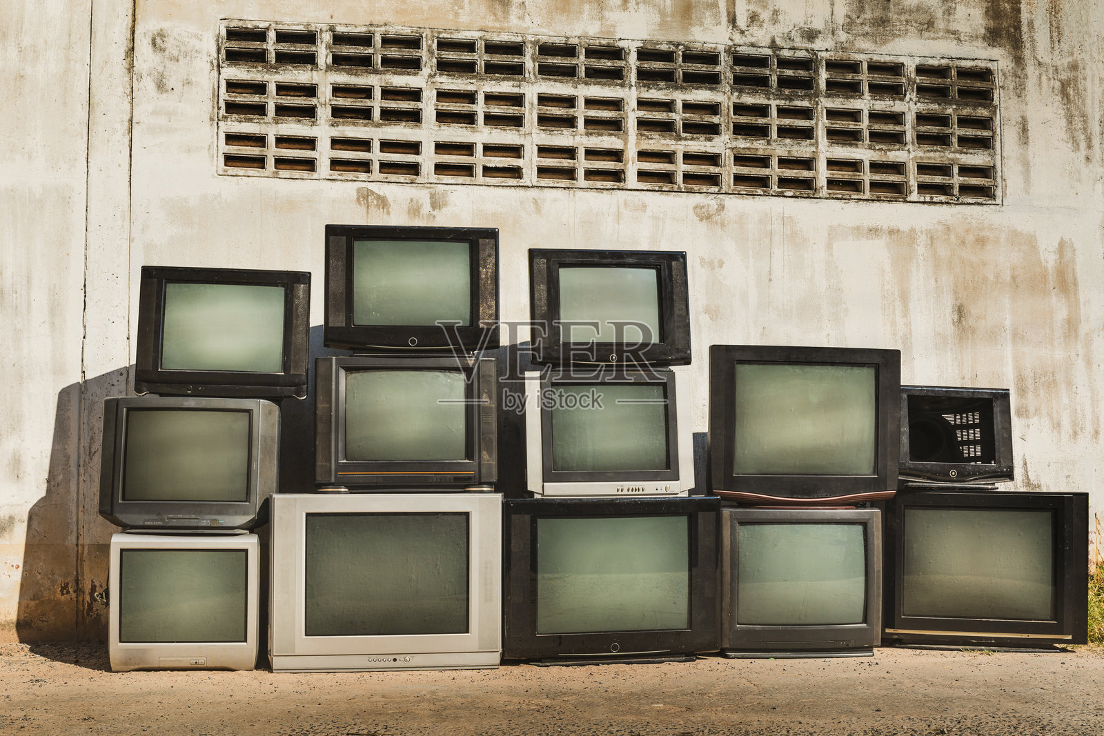 复古旧电视机堆放在旧墙前。叠放的电视机带有复古滤镜效果。照片摄影图片