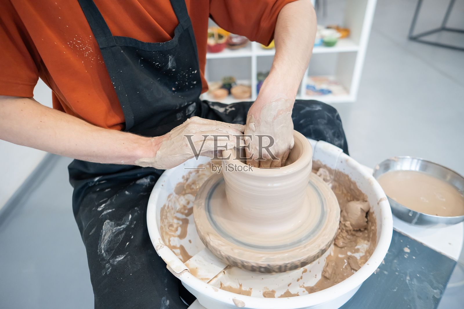 陶艺师的双手在陶轮上制作陶瓷花瓶的特写镜头。照片摄影图片