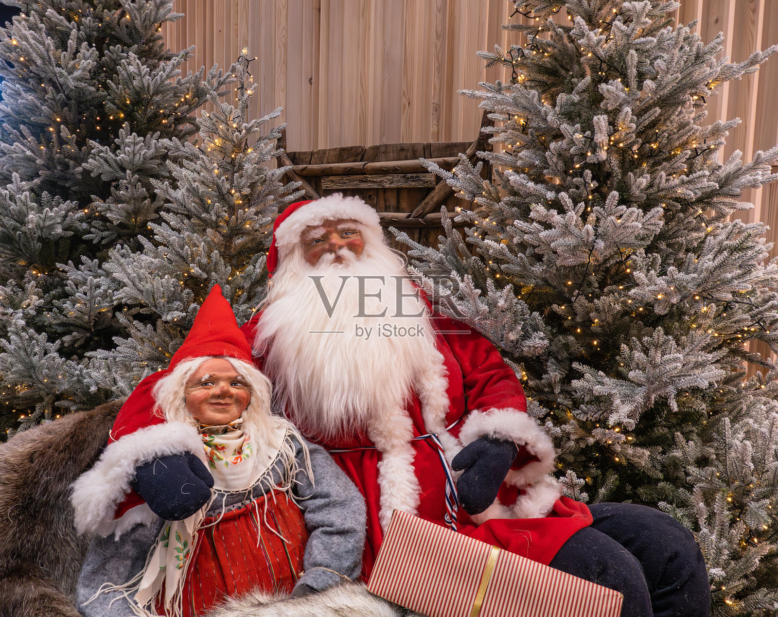 圣诞老人和克劳斯夫人站在装饰着灯光的雪白圣诞树旁照片摄影图片