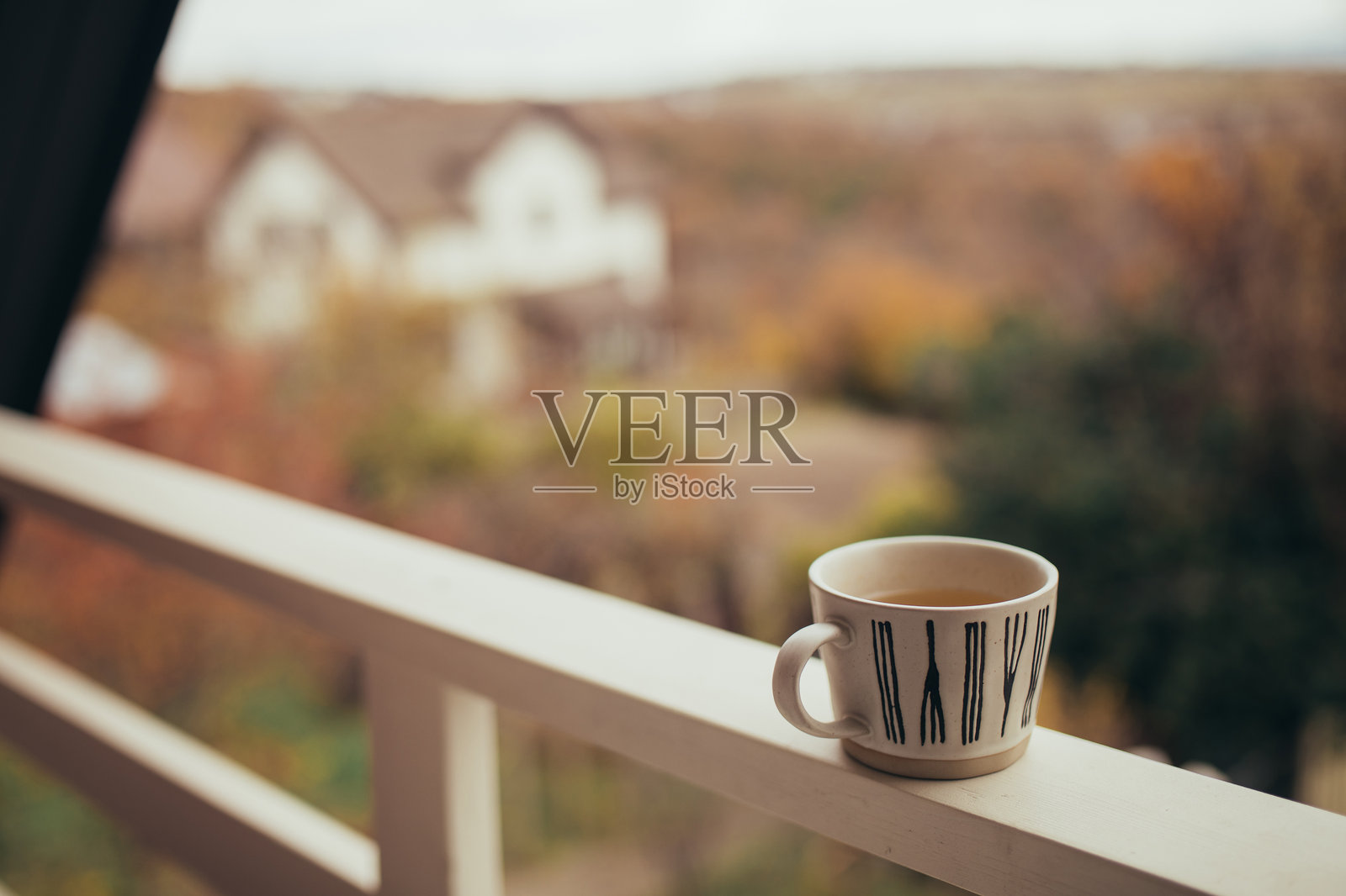 温暖的木屋阳台上放着一杯热草药茶。照片摄影图片