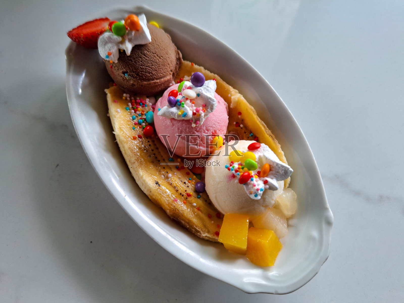 美味的香蕉船冰淇淋，配有香蕉、草莓、芒果、鲜奶油、糖果、巧克力冰淇淋、草莓冰淇淋和香草冰淇淋。甜点菜单。照片摄影图片