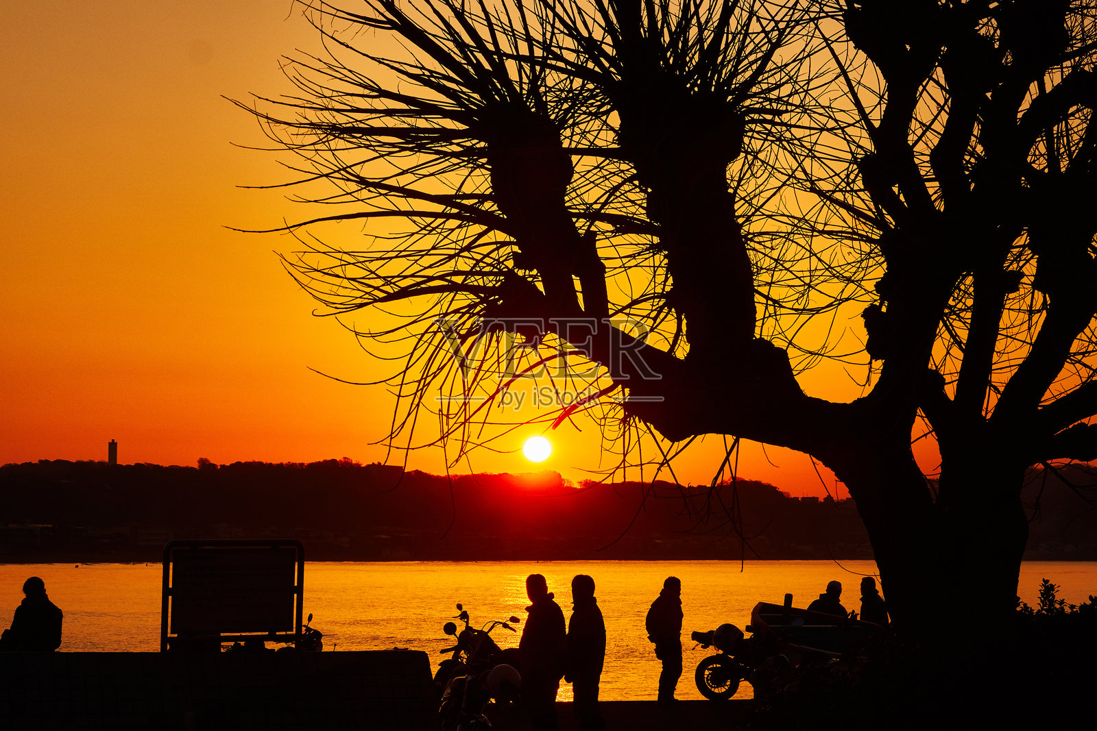 日出时分，海滩的美丽景色，剪影般的人们在阴郁的天空下伫立。照片摄影图片